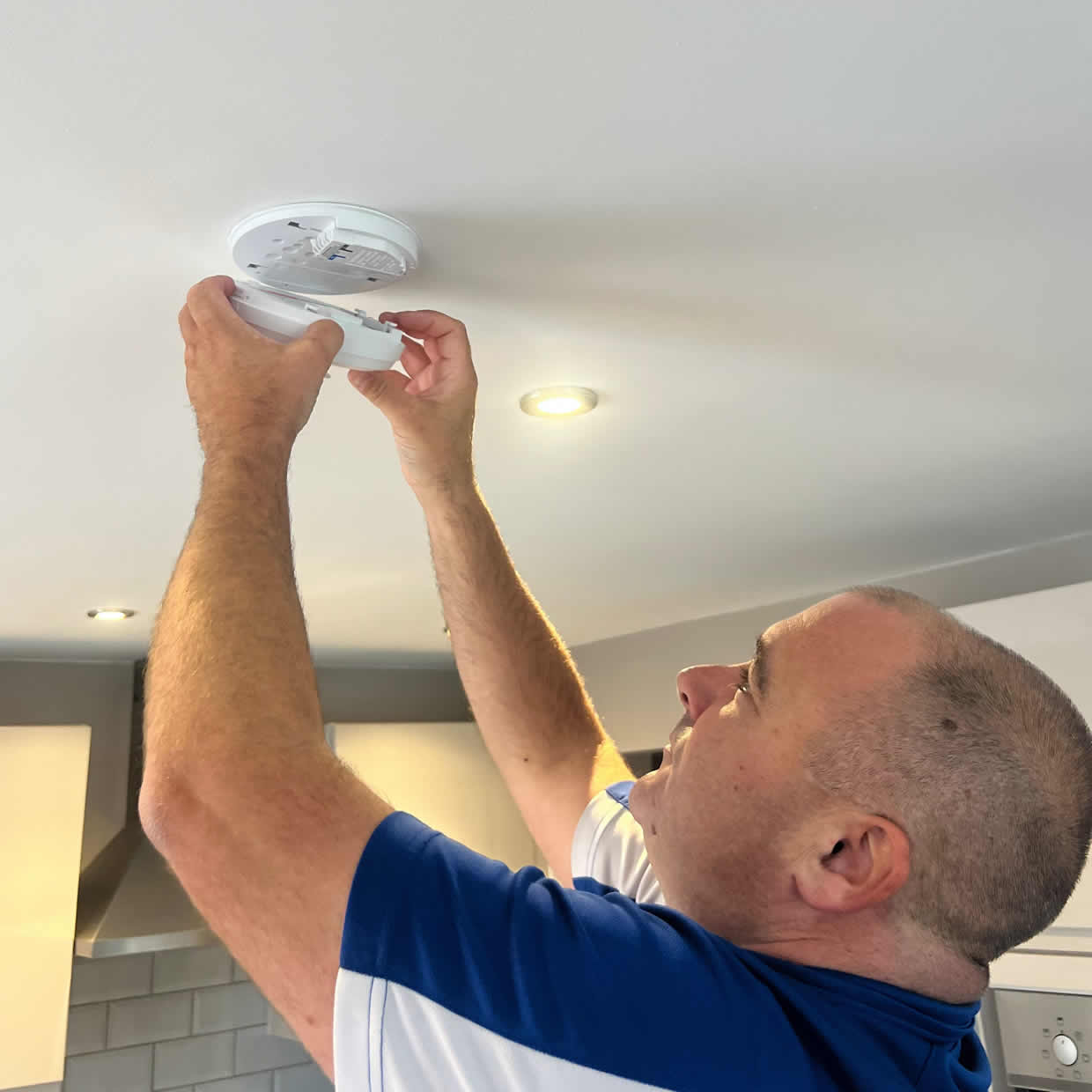 Smoke alarm installer fitting an alarm in an Ashton-under-Lyne property